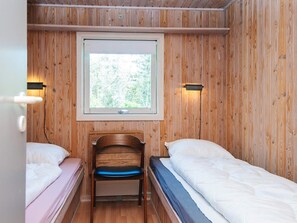 Ein kleines, gemütliches Zimmer mit zwei Einzelbetten, einem Holzstuhl und einem Fenster für natürliches Licht.