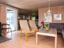 Amplia sala de estar con suelo de madera, una mesa de comedor, dos sillas, un sofá y una lámpara colgante.