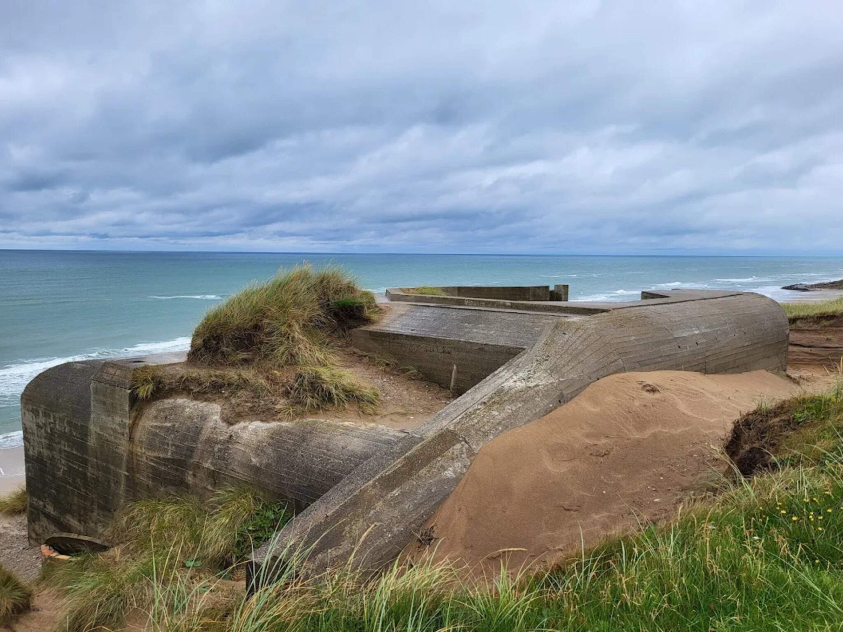 A coastal landscape with concrete structures, grassy areas, and the ocean.