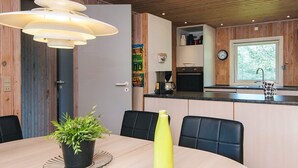 Moderni keittiö, jossa on puukalusteet, sisäänrakennettu uuni ja kahvinkeitin.