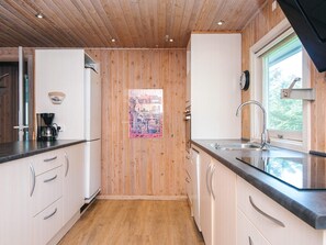 Een moderne keuken met houten paneelwanden, een koffiezetapparaat, een spoelbak en een raam met uitzicht.