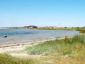 A riverside view with a building and wind turbines in the background. - 5 Star Holiday Home in Ebeltoft (Ebeltoft)