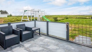 A patio with outdoor furniture, a playground, and a view of the countryside. - 5 Star Holiday Home in Ebeltoft (Ebeltoft)