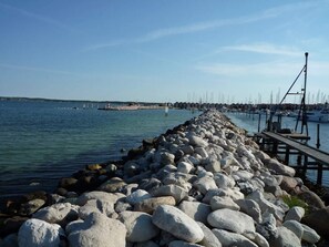 A rocky pier extending into calm waters with boats docked on the right. - 5 Star Holiday Home in Ebeltoft (Ebeltoft)