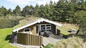 A wooden cabin with a deck, a patio area, and a large window.