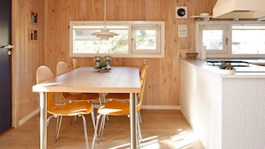 A wooden interior with a dining table, chairs, and a kitchen area.