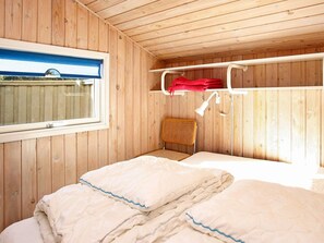 A wooden cabin room with a bunk bed, a window, a chair, and a lamp. - 4 Star Holiday Home in Blokhus (Blokhus)