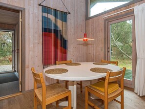 A round dining table with four chairs, a woven placemat, and a hanging light fixture.