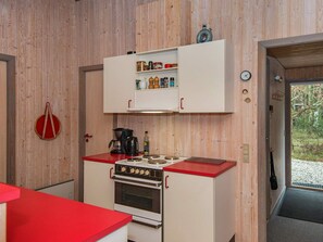 A compact kitchen with a stove, a coffee maker, and a cabinet with various items.
