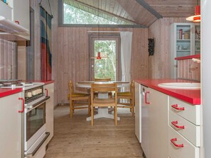 Una cocina compacta con una mesa de comedor, sillas de madera y una ventana con cortinas.