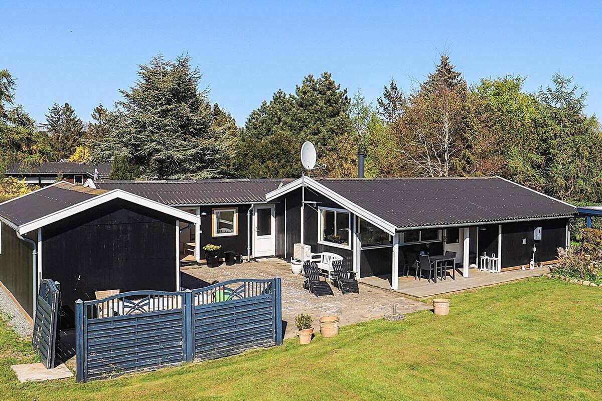 A two-story building with a covered patio, a garage, and a fenced area with outdoor furniture.