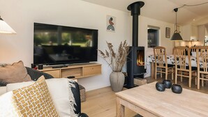 A living room with a TV, sofa, table, and a fireplace. - 4 Star Holiday Home in Dannemare (Dannemare)