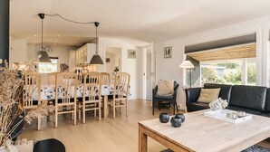 A modern living room with a dining area, a sofa, and a coffee table. - 4 Star Holiday Home in Dannemare (Dannemare)