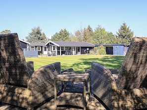 Wicker furniture in a backyard with a house in the background.