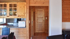 A wooden cabin interior with a kitchen area, dining table, and chairs. - 4 Star Holiday Home in Leikanger (Sogndal)