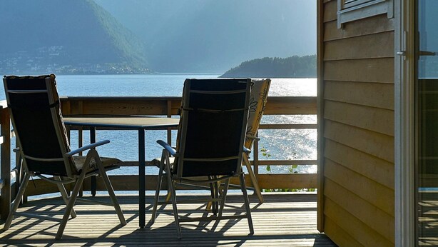A wooden deck with two chairs facing a scenic view of a lake and mountains. - 4 Star Holiday Home in Leikanger (Sogndal)