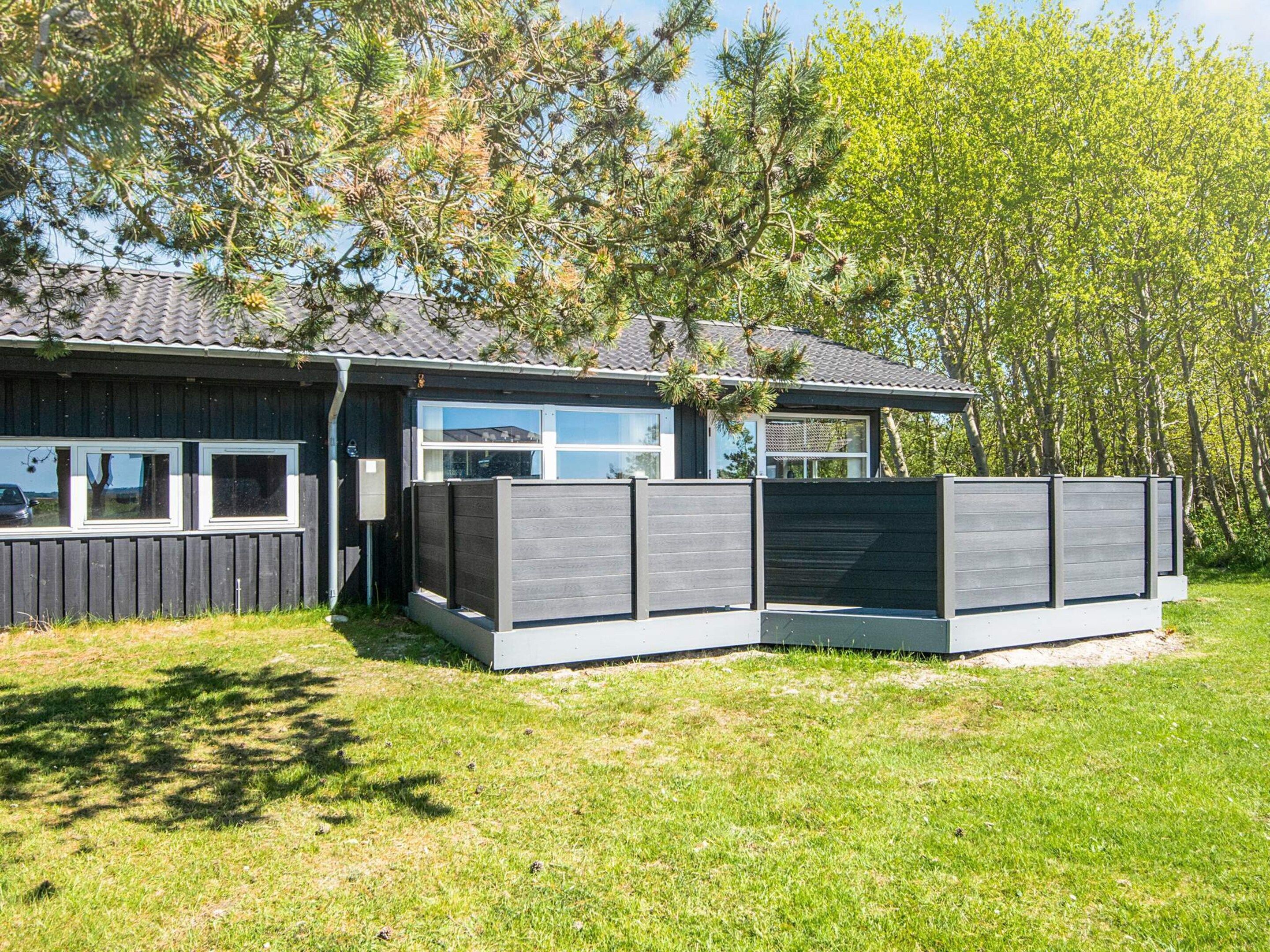 Ein modernes Haus mit umzäunter Garten, großen Fenstern und einer Garage.