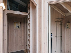Un intérieur en bois avec un tableau encadré au mur, un porte-manteau et un petit meuble contenant un objet décoratif.