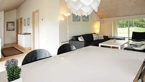En moderne stue med et hvidt bord, en sort sofa og en unik hvid loftslyse.