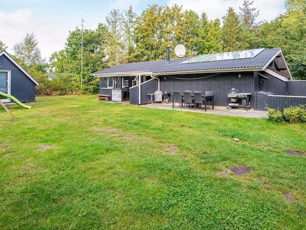 A two-story building with a covered patio area, a barbecue grill, and a satellite dish.