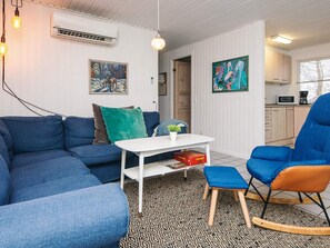 A modern living room with a sectional sofa, a rocking chair, a small table with a plant, and artwork on the walls.