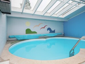 An indoor swimming pool with a clear ceiling and a mural on the wall.