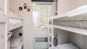 Ein Schlafsaalzimmer mit Etagenbetten, einem Fenster mit Blick auf Bäume und einem Heizkörper.