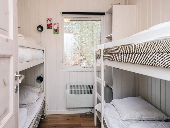 A dormitory room with bunk beds, a window with a view of trees, and a radiator.