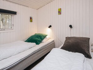 A room with two beds, one with a green pillow and the other with a brown pillow. There are two wall-mounted lamps. - 8 Person Holiday Home in Orsted (Ørsted)