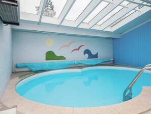 A swimming pool with a clear blue water surface, a metal ladder, and a mural on the wall depicting a sun, birds, and waves. - 8 Person Holiday Home in Orsted (Ørsted)