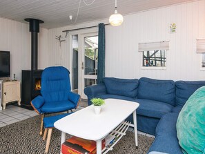 A cozy living room with a blue armchair, a blue sofa, a white coffee table, and a fireplace. - 8 Person Holiday Home in Orsted (Ørsted)