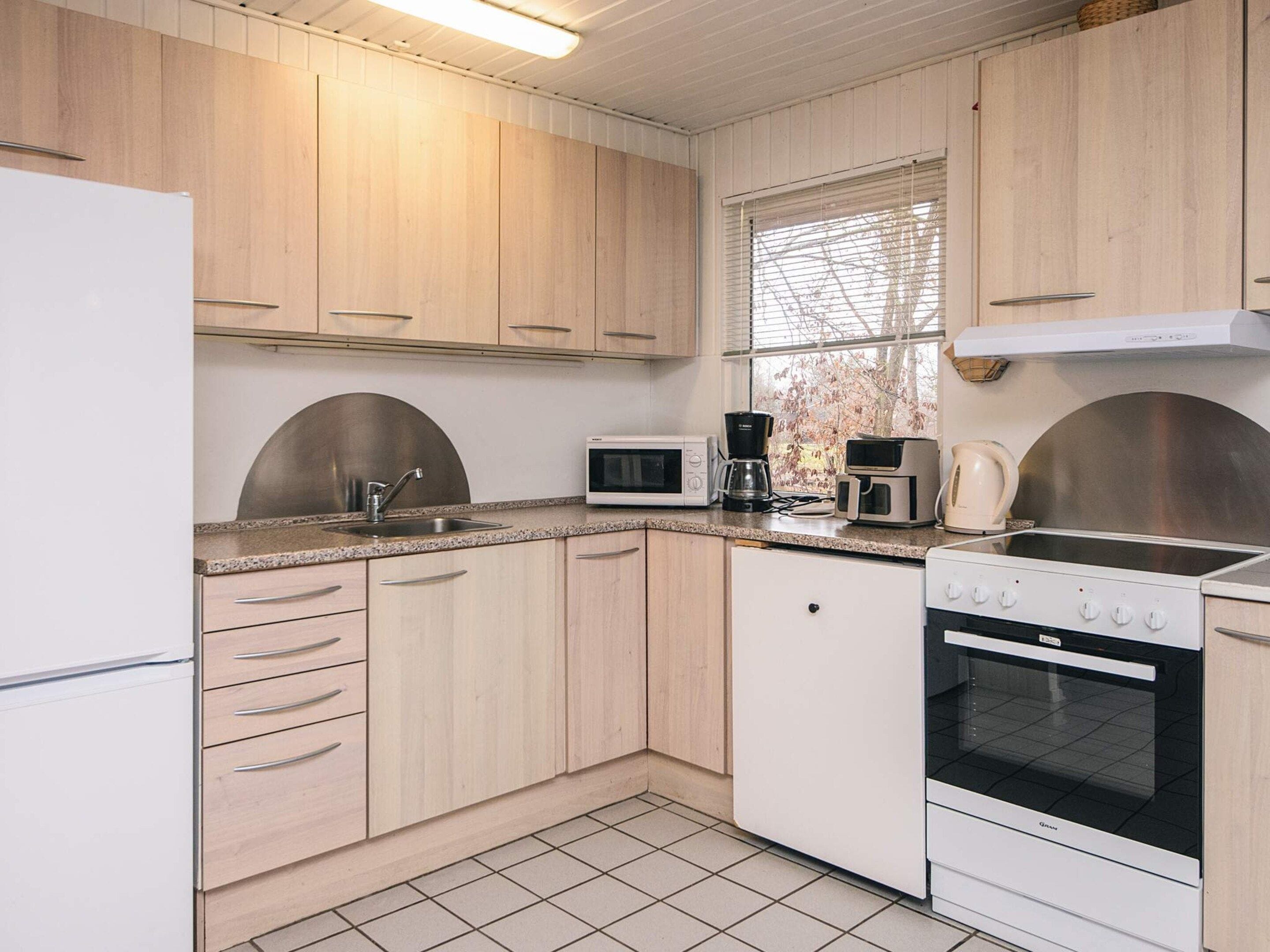 A compact kitchen with wooden cabinets, a microwave, a coffee maker, a toaster, and a stove.