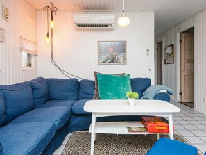 A modern living room with a blue sectional sofa, a white coffee table, and a patterned rug.