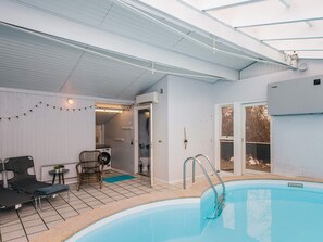 A swimming pool with a sunroof, a lounge area with chairs and a table, and a laundry room with a washing machine. - 8 Person Holiday Home in Orsted (Ørsted)