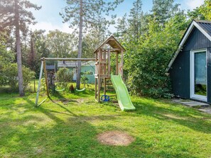 A playground with swings, a slide, and a small wooden structure.