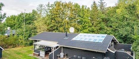 A modern house with a large patio, a covered outdoor seating area, and a solar panel roof.