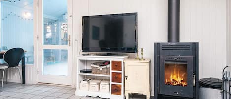 A living room with a television on a white cabinet, a fireplace, and a door leading outside.