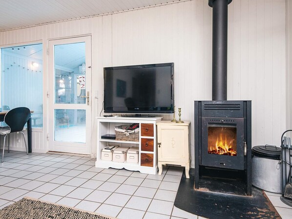 A living room with a television on a white cabinet, a fireplace, and a door leading outside.