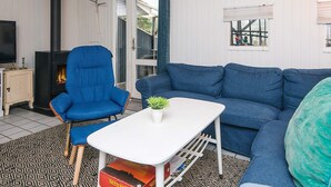Ein Wohnzimmer mit einem blauen Sofa, einem blauen Sessel, einem weißen Couchtisch, einem Fernseher und einem Kamin.