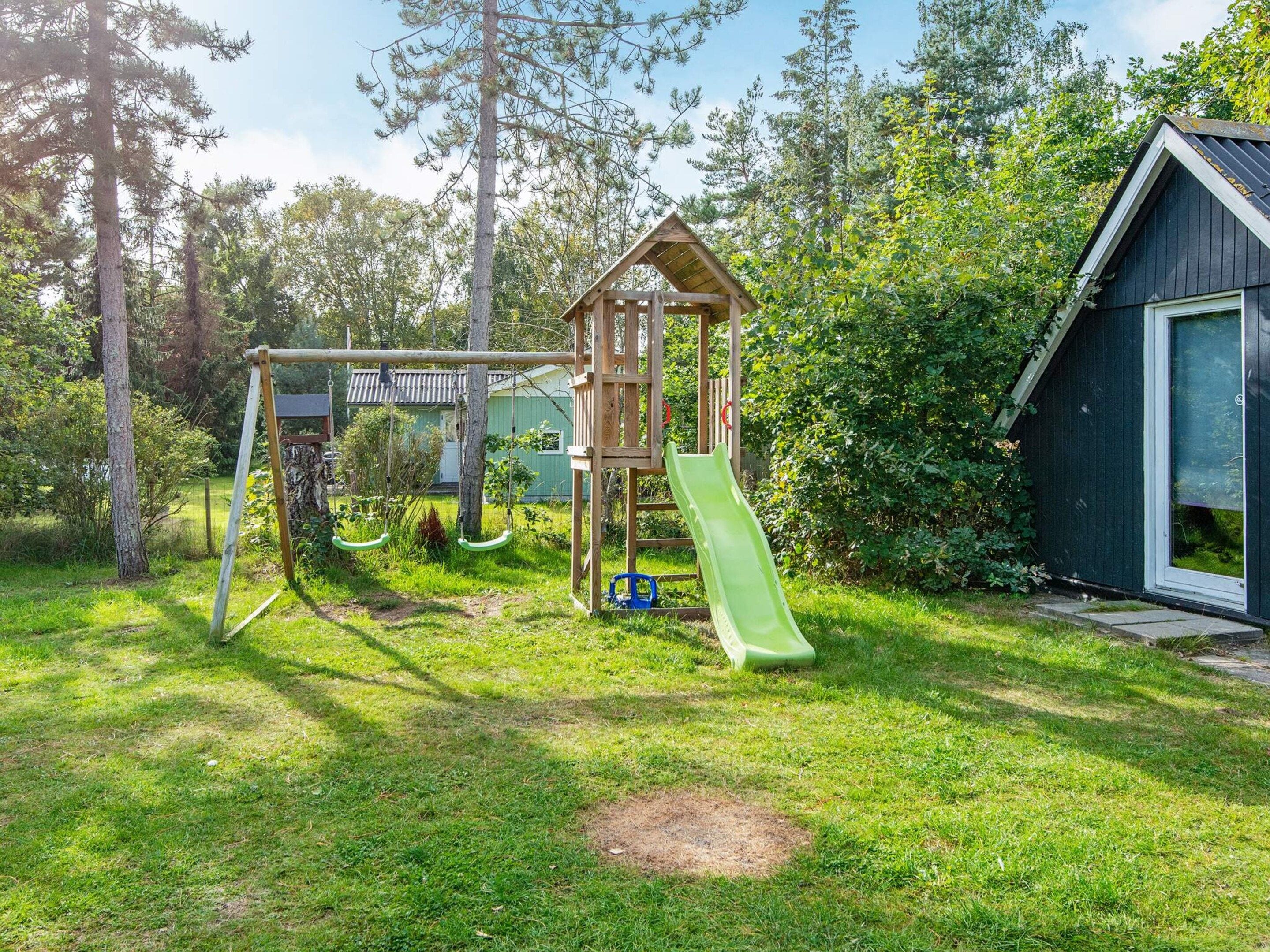 A playground with swings, a slide, and a small wooden structure.
