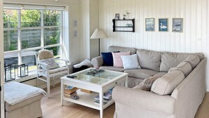 A cozy living room with a sofa, armchair, and coffee table, featuring a view through large windows. - 8 Person Holiday Home in Broager-by Traum (Broager)