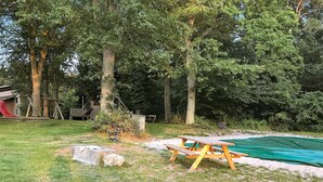 A backyard with a swimming pool, a picnic table, and a playground.