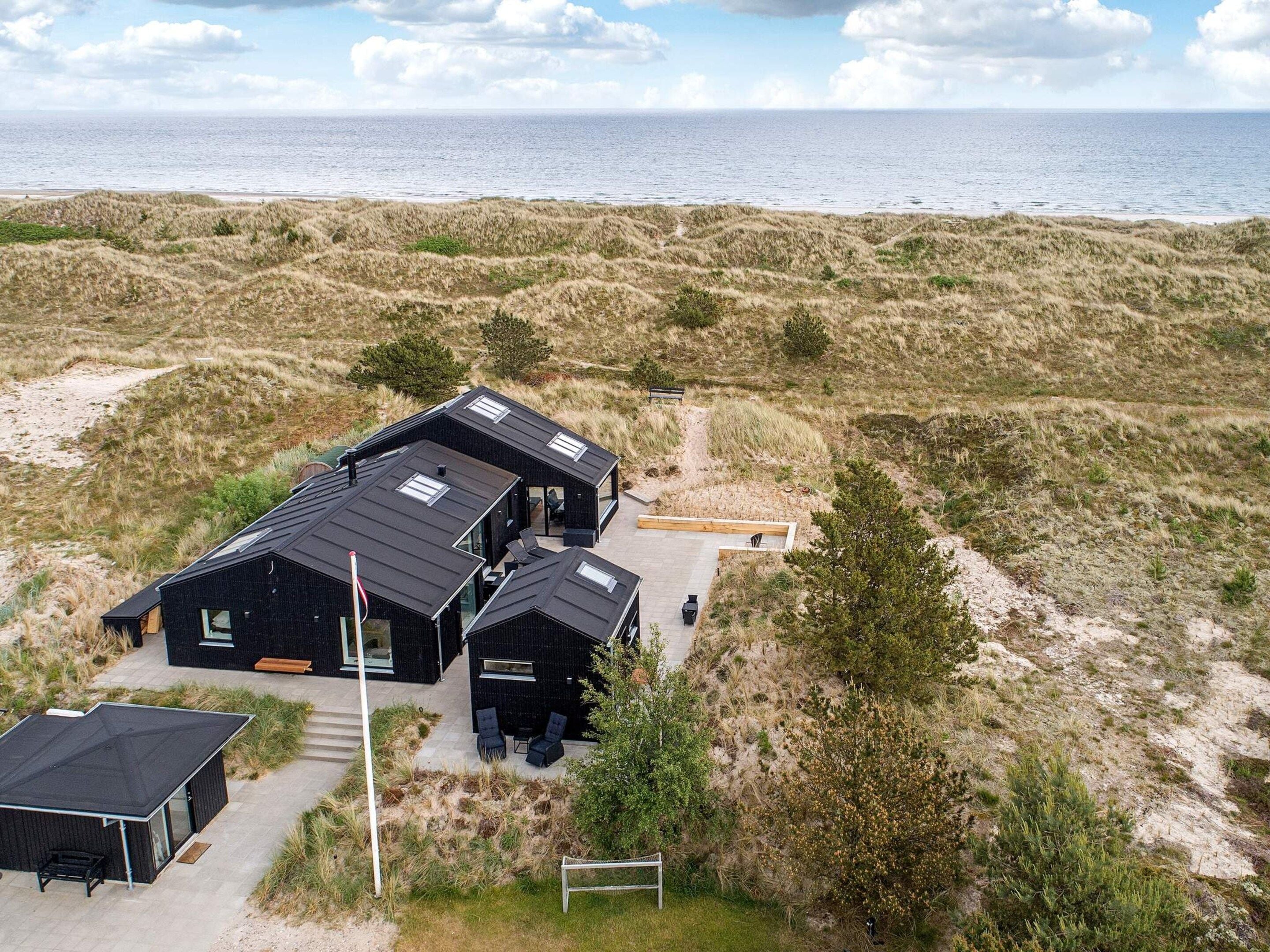 Et moderne sommerhus med flere værelser, en terrasse og havudsigt.