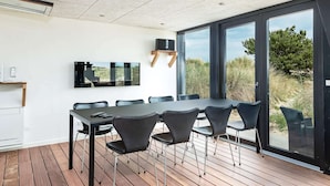 A modern meeting room with a large table and chairs, a flat-screen TV, and a view of the outdoors. - 5 Star Holiday Home in Albaek (Aalbaek)