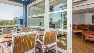 Une terrasse extérieure avec des meubles en bois et de grandes fenêtres.