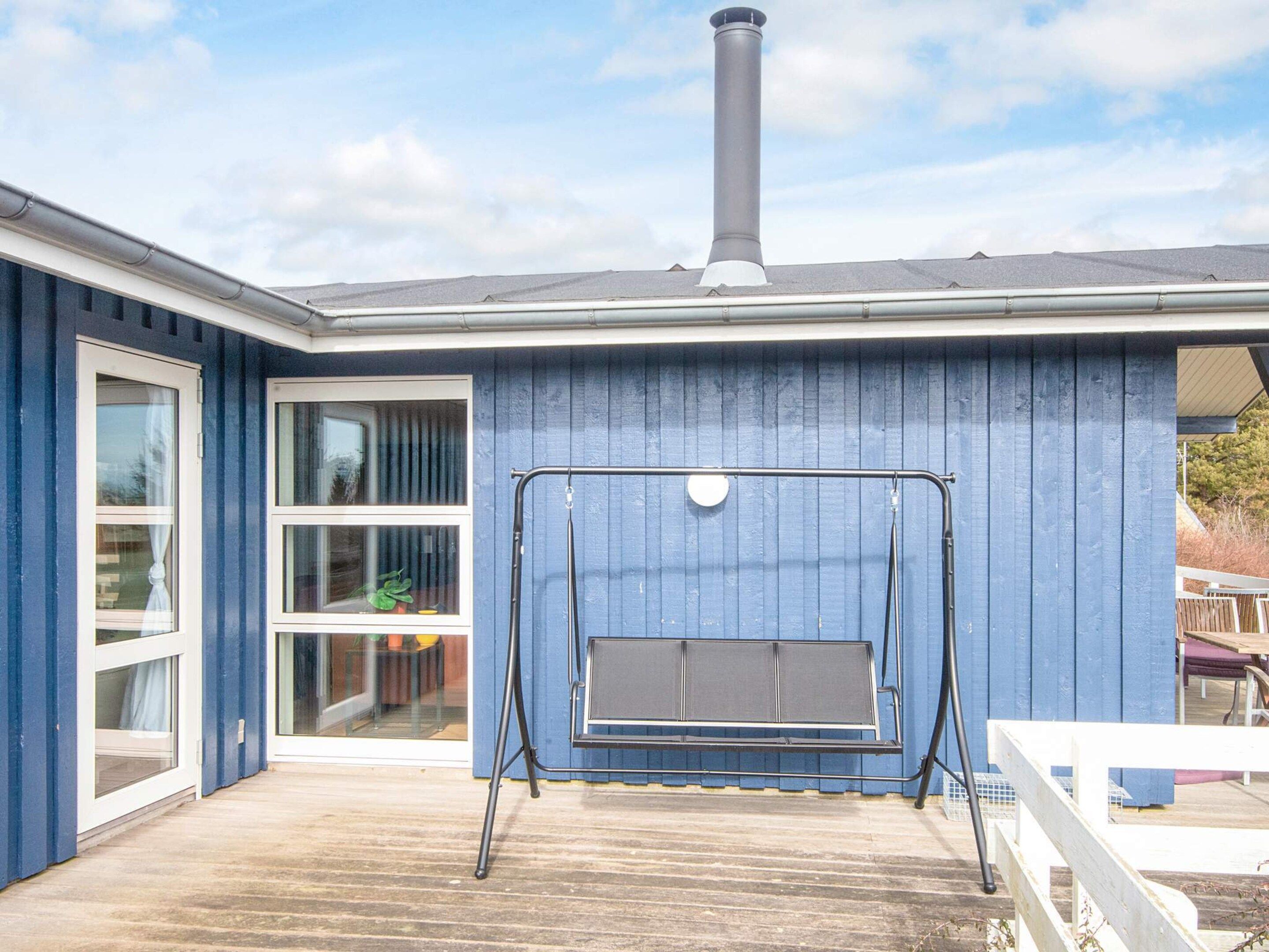 A house with a blue exterior, a chimney, and a swing set in the backyard.