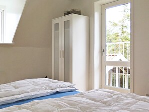 Une chambre à coucher avec un lit, une armoire et une fenêtre donnant sur un paysage verdoyant.