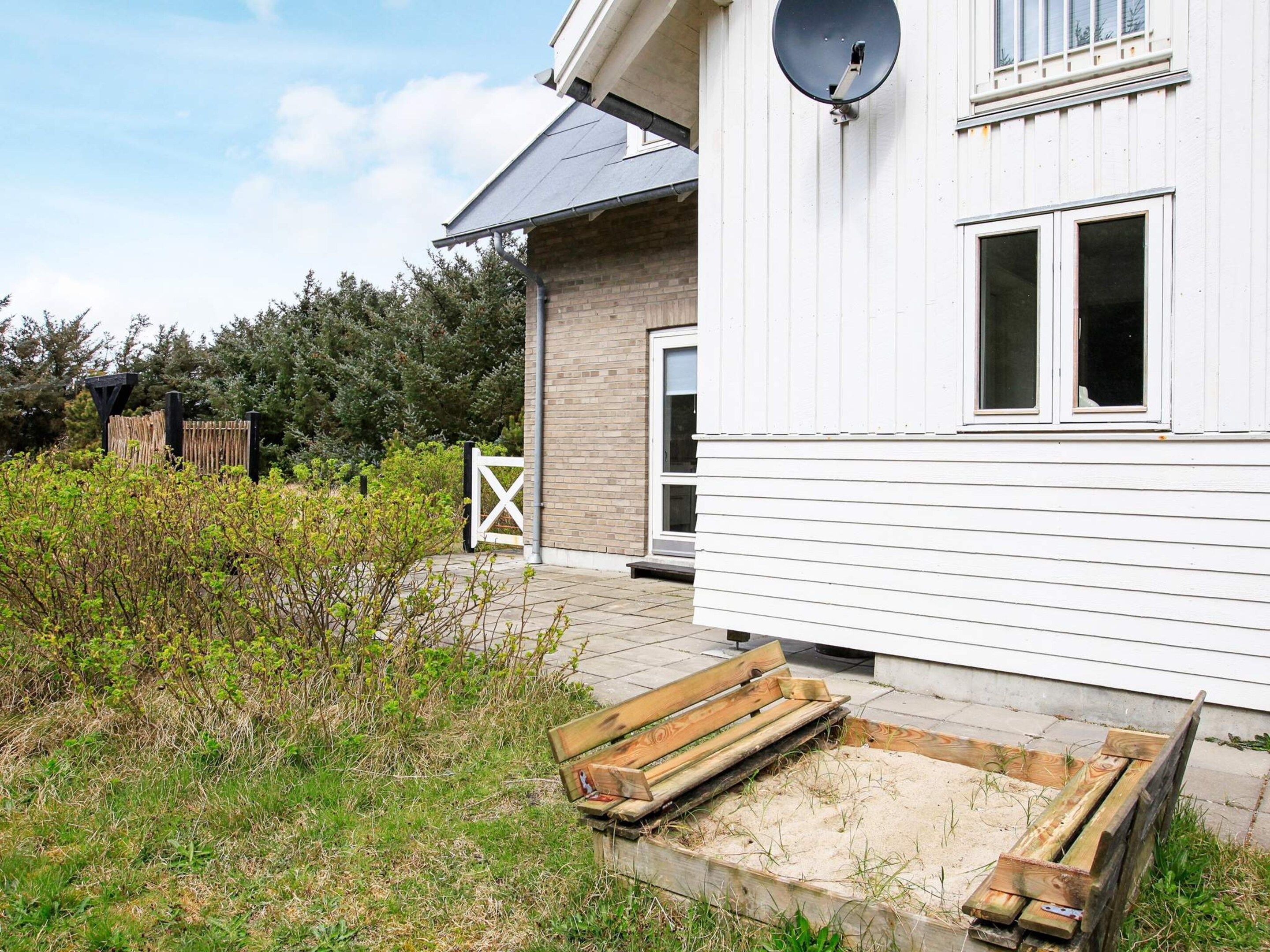 A residential building with a satellite dish, a wooden bench, and a gated entrance.