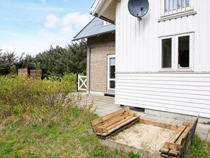 Un immeuble résidentiel doté d’une antenne parabolique, d’un banc en bois et d’une entrée fermée par un portail.