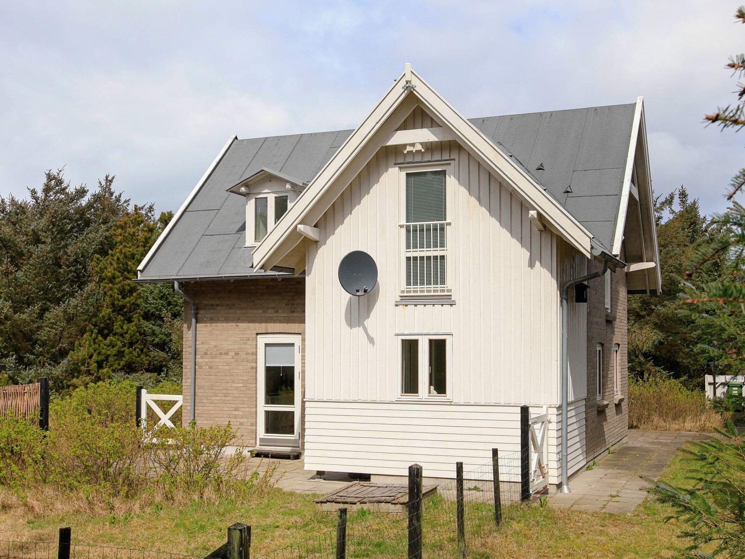 A single-story house with a gabled roof, a front door, and a satellite dish.